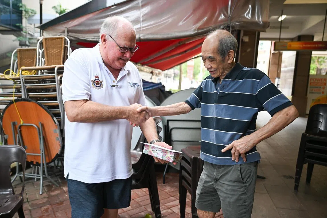 Retired pilot Ronald Haack (left) presenting an air force medallion to restaurant owner Au Kok Wing.