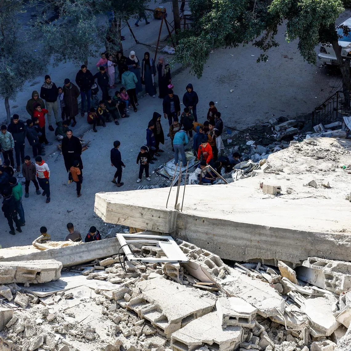Palestinians at the site of a collapsed house that was damaged during the war by an Israeli strike, in the central Gaza Strip, January 5, 2026. REUTERS/Mahmoud Issa