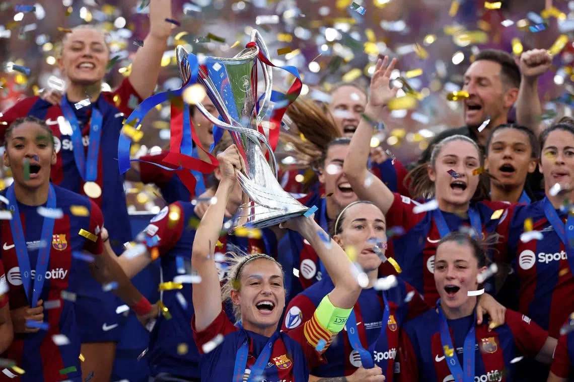 Barcelona's Alexia Putellas lifts the trophy as she celebrates winning the Champions League with teammates.