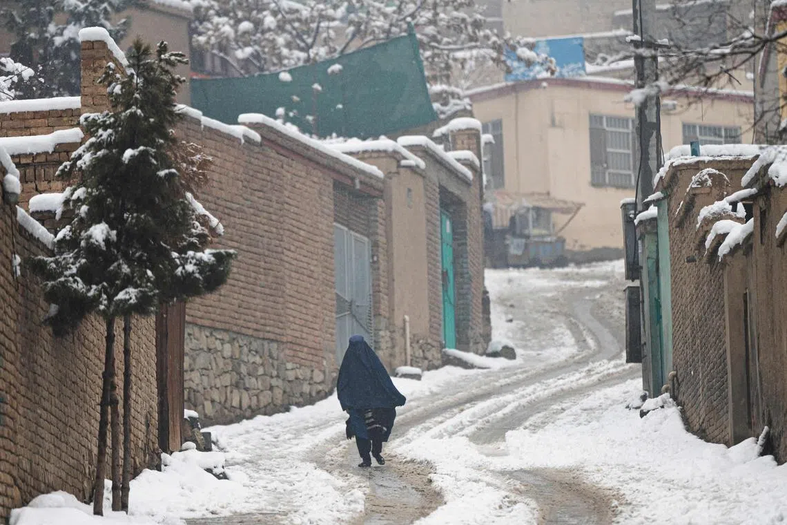 A burqa-clad woman walks along a street during snow fall in Kabul on January 11, 2023. (