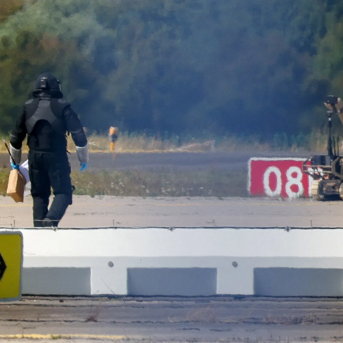 A police officer in protective clothing walks next to an explosive-disarming robot at Leipzig/Halle Airport on Aug 5.