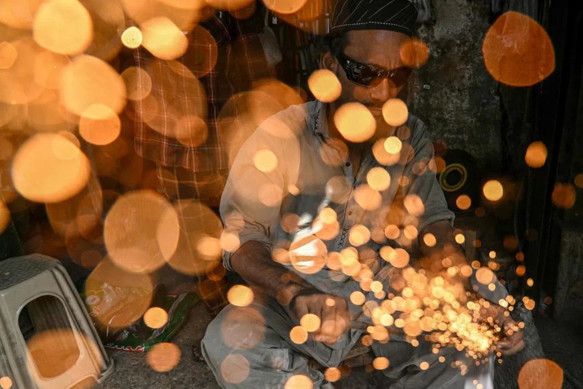 A blacksmith sharpening knives at a shop ahead of the Muslim festival of Eid al-Adha in Karachi on June 5, 2025.