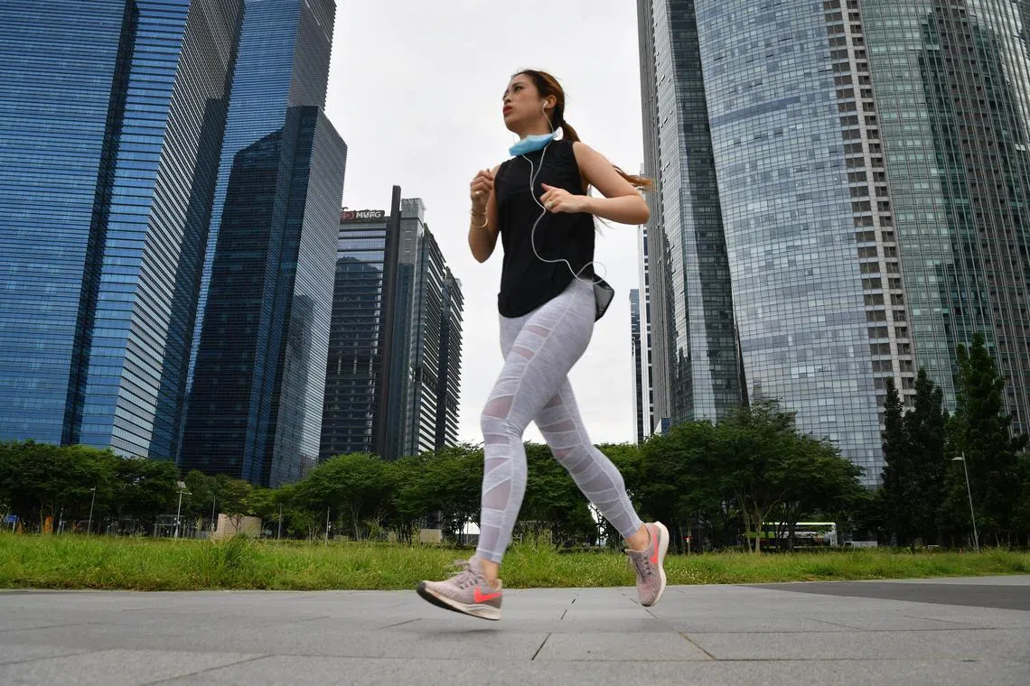 A lady jogging with a mask around her neck at the promontory @ Marina Bay at 5.15pm on June 6, 2020. 