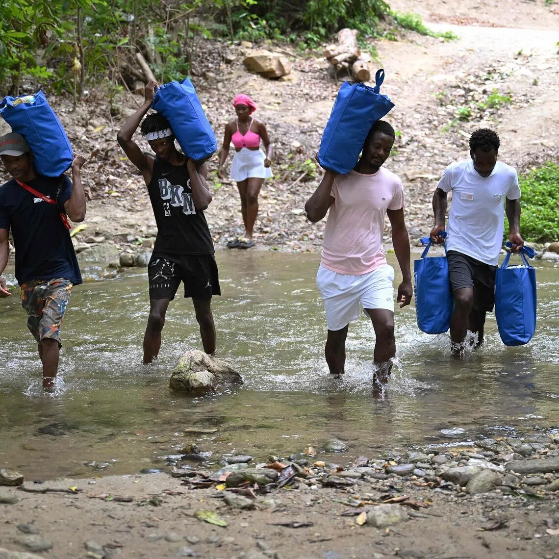 Wilfrank Liendo (second from right) and other locals carry supplies donated by the World Food Programme to their home in Chichiriviche de la Costa, La Guaira state, Venezuela, on July 16, following the June 24 earthquakes.
