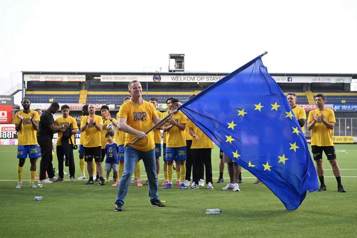 STVV's Belgian headcoach Wouter Vrancken waves an European Union flag as he celebrates at the end of the Belgian Pro League Champions' play-off (day 10 out of 10) football match between Sint-Truidense Voetbalvereniging (STVV) and KV Mechelen at the Daio Wasabi Stayen Stadium in Sint-Truiden on May 24, 2026. (Photo by JOHN THYS / BELGA / AFP) / Belgium OUT