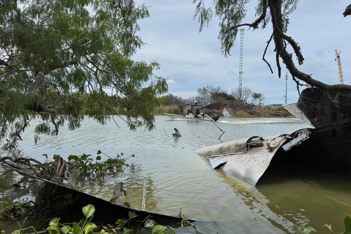 FILE PHOTO: Debris from a SpaceX spacecraft lies partially submerged in the Rio Grande River as a boat navigates nearby, as seen from Matamoros, Mexico, June 19, 2025. REUTERS/Abraham Pineda/File Photo
