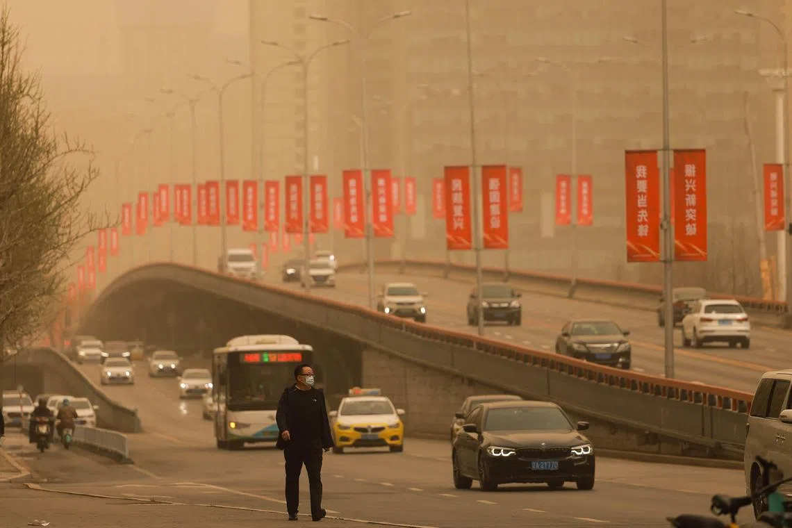 People commute on a street during a sandstorm in Shenyang, in China's northeastern Liaoning province on April 11, 2023. (Photo by AFP) / China OUT