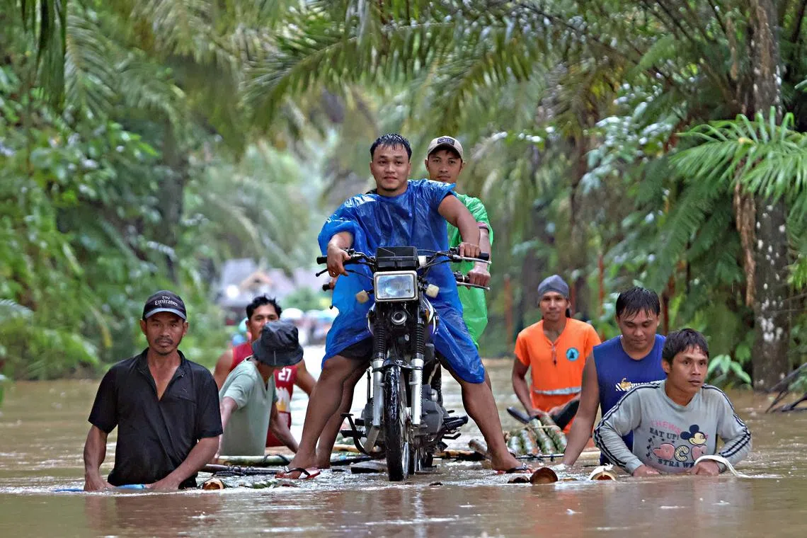 Residents push a makeshift raft loaded with a motorcycle through floodwaters brought about by heavy rains in Propseridad town, Agusan del Sur province on southern Mindanao island on February 1, 2024. Floods and landslides triggered by torrential rain have killed six people in the Philippines, with one other person missing, rescuers said February 1. (Photo by Erwin MASCARINAS / AFP)