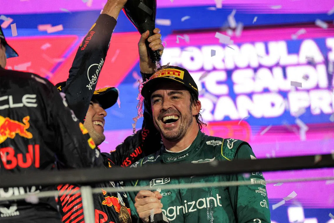 Aston Martin's Fernando Alonso celebrating on the podium with Red Bull's Sergio Perez at the Saudi Arabia Grand Prix.
