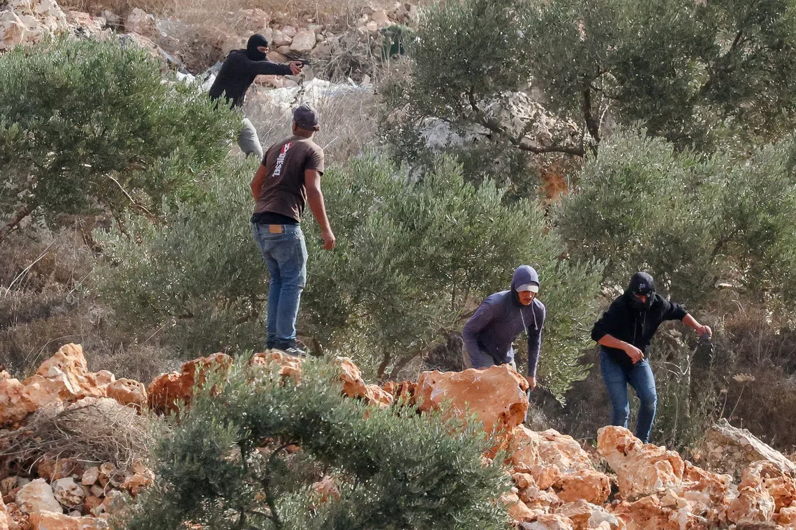 An Israeli settler points a gun amid clashes with Palestinians harvesting olives in Abu Falah near Ramallah in the Israeli-occupied West Bank, October 16, 2026. REUTERS/Ammar Awad