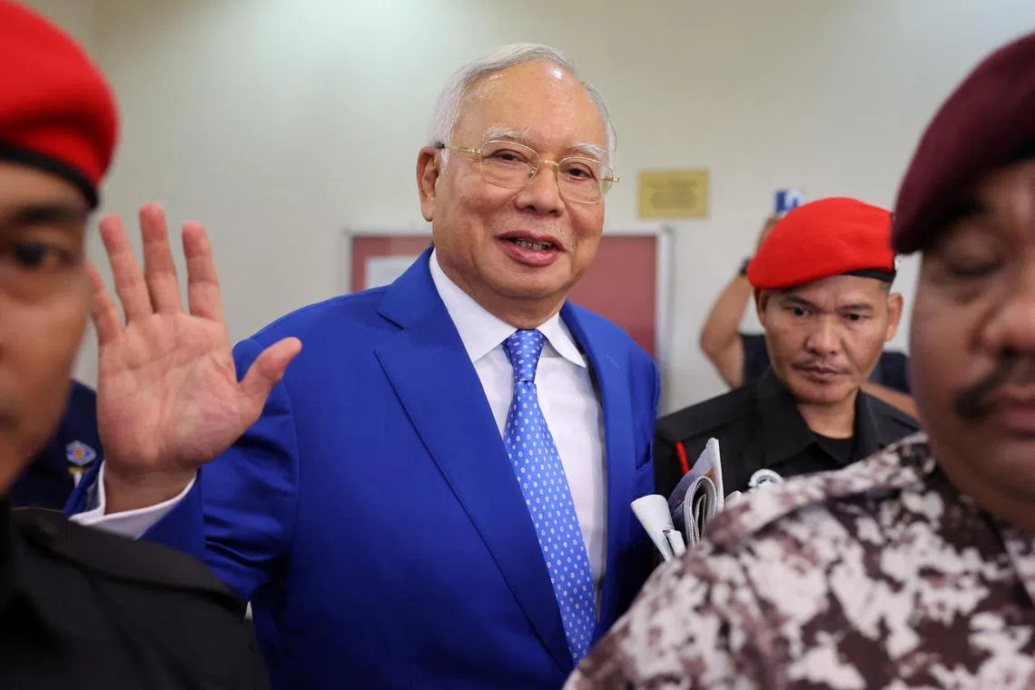Former Malaysian Prime Minister Najib Razak escorted by prison officers, waves to photographers as the jailed politician leaves the court after court proceedings in Kuala Lumpur, Malaysia January 19, 2024. REUTERS/Hasnoor Hussain