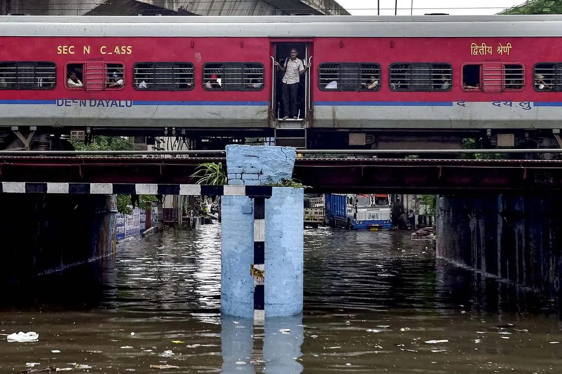 A train crosses over a flooded railway bridge during heavy rainfall in Jalandhar on Aug 14.