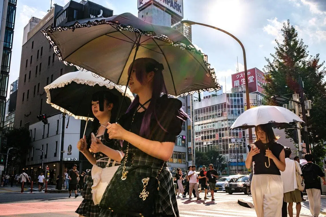 Pedestrians holding umbrellas walk on a hot day amid a heatwave in Tokyo's Shinjuku district on August 30, 2025. (Photo by Philip FONG / AFP)