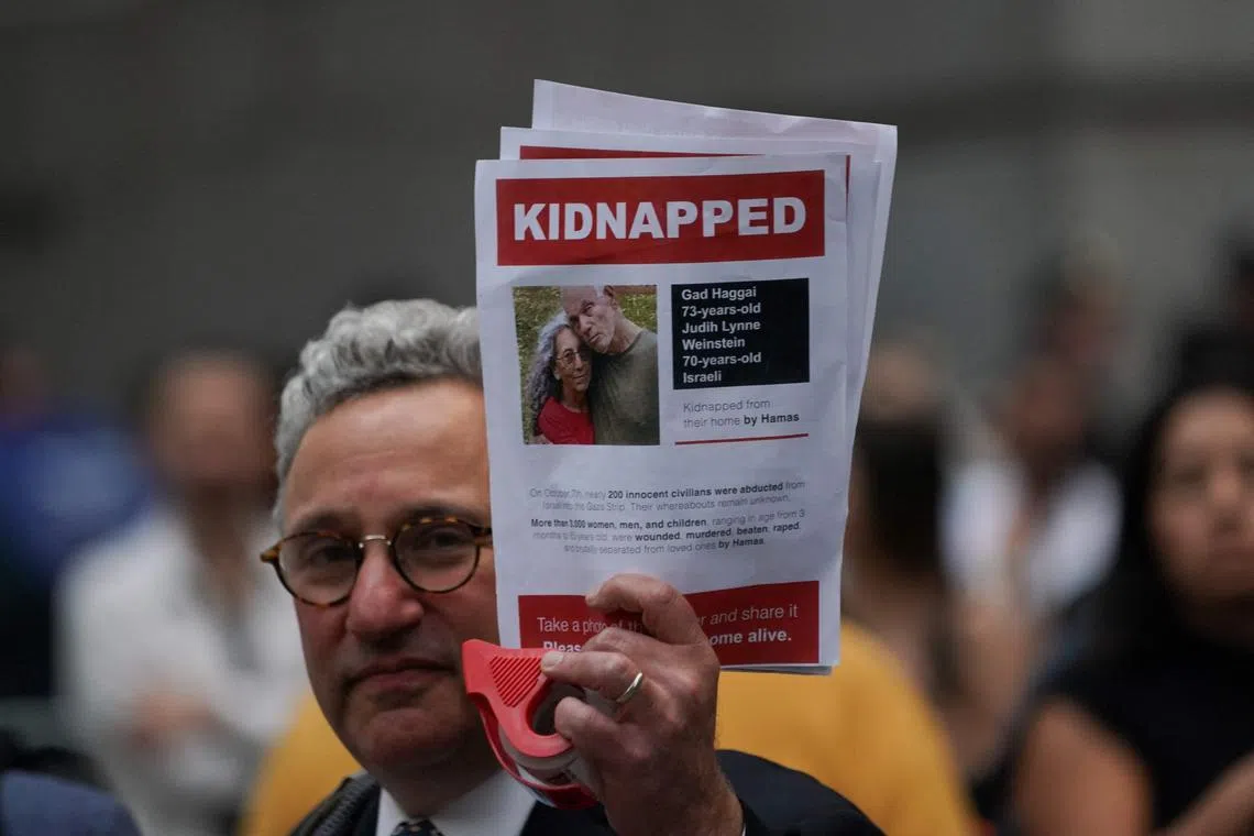 A protester at a rally in New York holds a picture of kidnapped Israeli hostages Gad Haggai and Judith Weinstein Haggai.