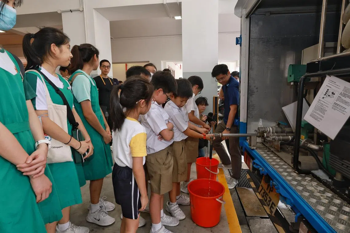 Kong Hwa School pupils (in white), accompanied by students from Tanjong Katong Girls’ School (in green), collecting water from a distribution point after experiencing water disruption in their school during the “Make Every Drop Count” water conservation campaign launched by Singapore’s National Water Agency PUB on March 8, 2023. ST Photo: Kevin Lim gswater08