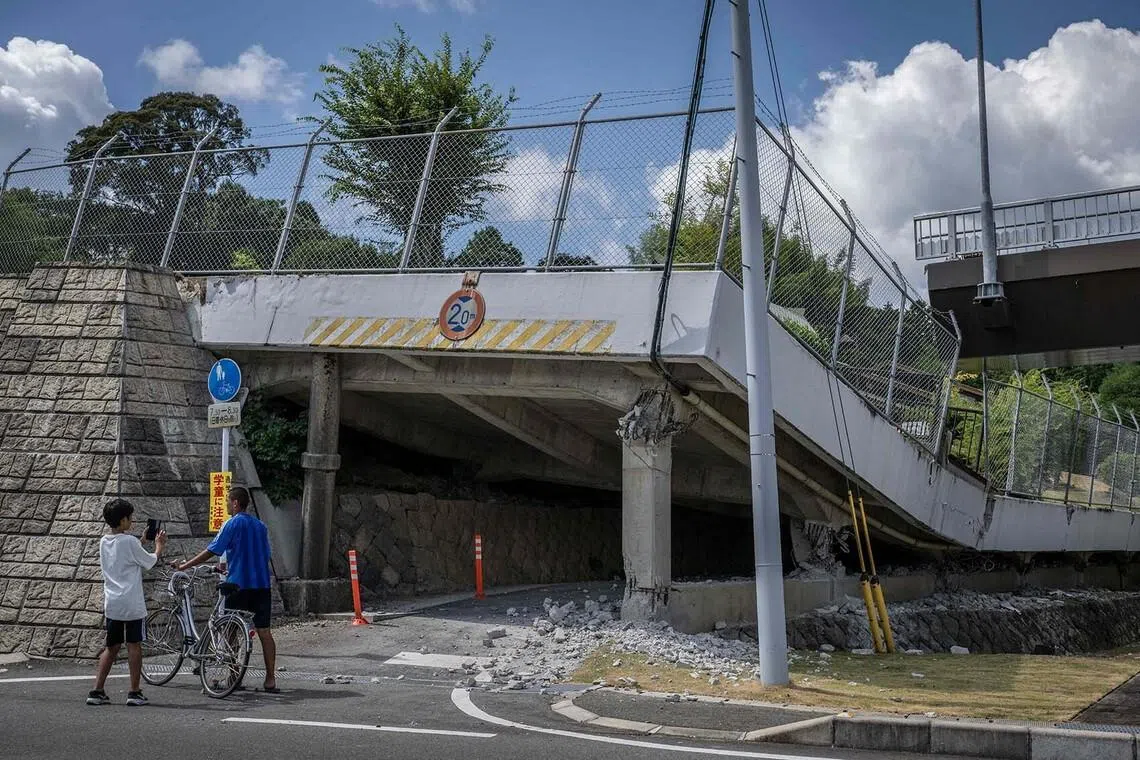 TOPSHOT - Children look at a section of a collapsed road in Hikawa town, Kumamoto prefecture on July 29, 2026, after an earthquake struck southwestern Japan the previous day. (Photo by Yuichi YAMAZAKI / AFP)
