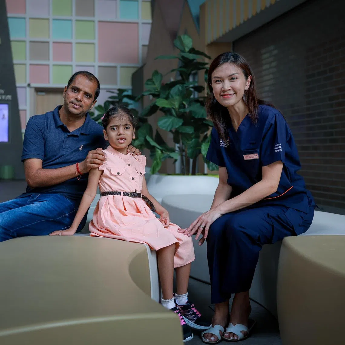 Mr Veerama Rao with his daughter Geethika Rao, 7, and her doctor Dr Chin Hui-Lin, Senior Consultant, Division of Genetics and Metabolism, Department of Paediatrics, Khoo Teck Puat - National University Children's Medical Institute, National University Hospital, at the hospital on March 29, 2025. Geethika suffers from Smith-Magenis Syndrome,