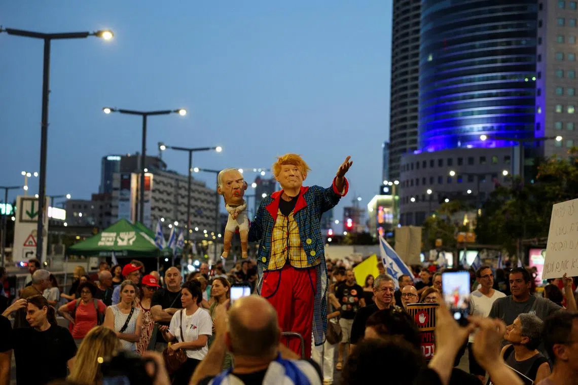 A demonstrator wears a mask of U.S. President Donald Trump and holds a prop baby with a mask of Israeli Prime Minister Benjamin Netanyahu, during a protest in Tel Aviv, Israel on June 28, to demand the immediate release of hostages held in Gaza.