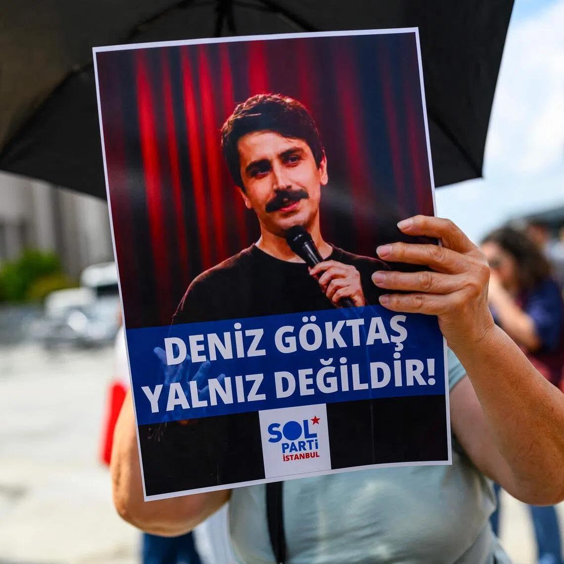 A Turkish leftist chants slogans for Turkish comedian Deniz Goktas, holding a banner reading “Deniz Goktas not alone” in front of the Caglayan Courthouse on July 3.