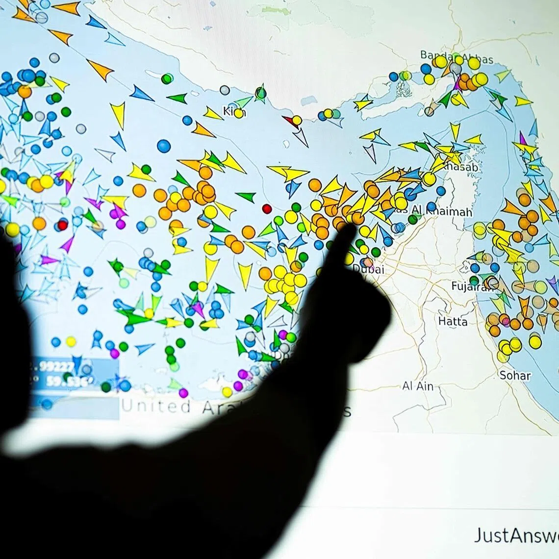 A large screen displaying vessel movements in the Strait of Hormuz on a ship-tracking website. 