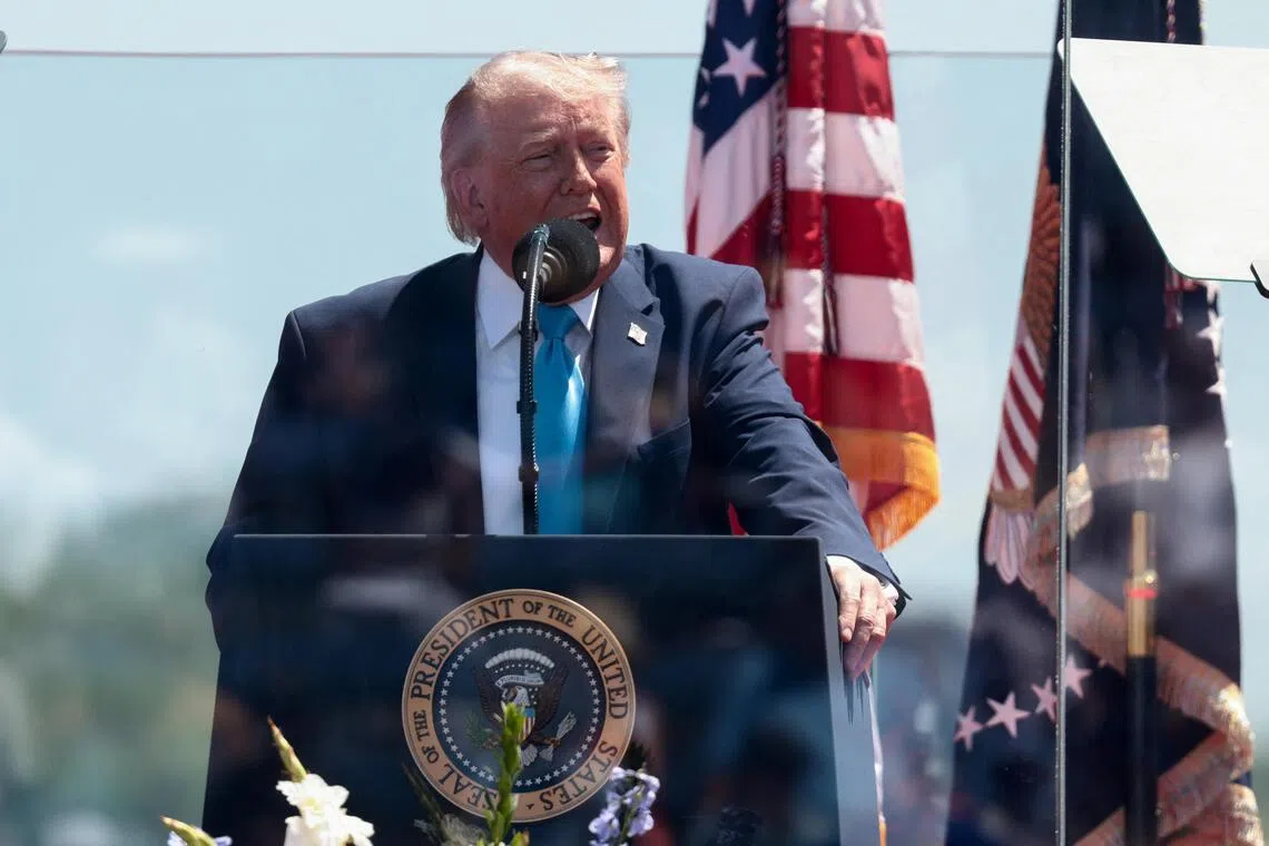 US President Donald Trump standing behind protective glass as he delivers the commencement address at the US Coast Guard Academy on May 20, in New London, Connecticut.