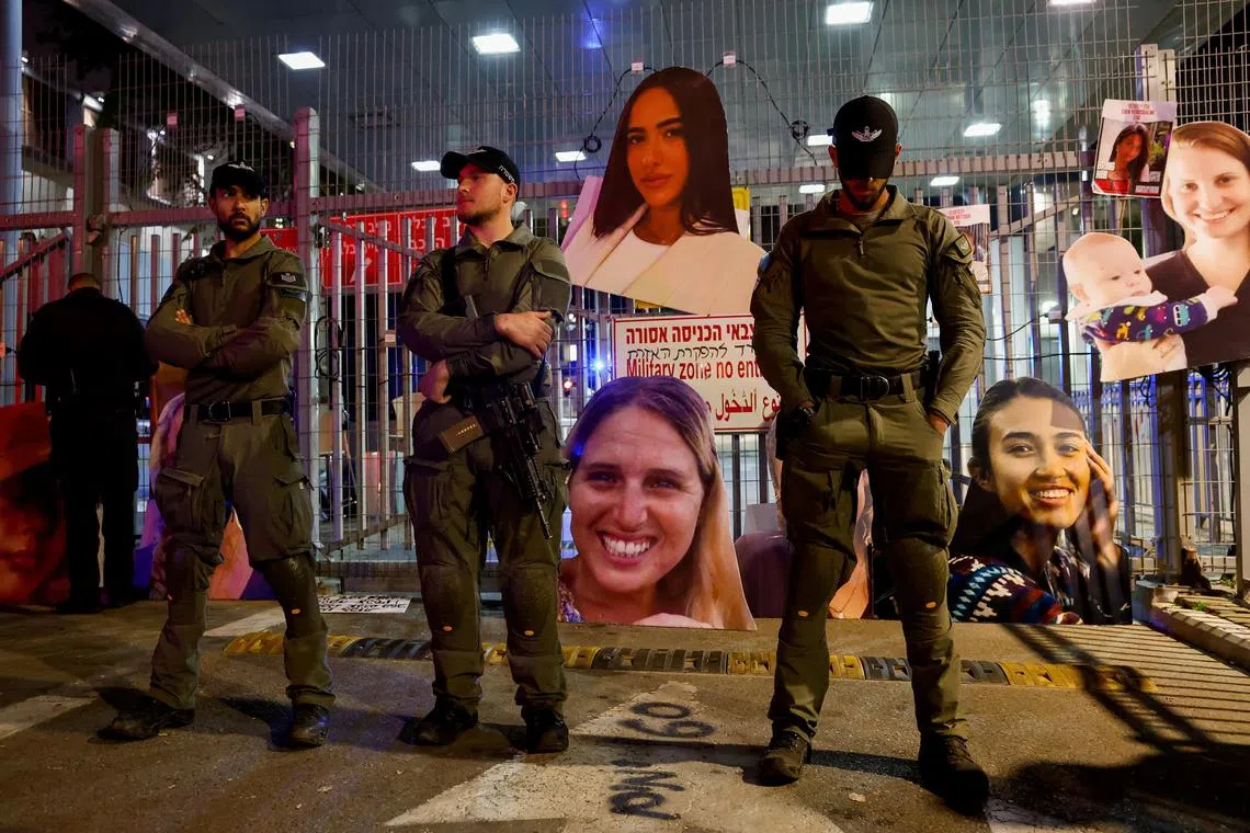 Officers stand guard next to photos of hostages taken by Hamas during its deadly Oct 7 raids into southern Israel.
