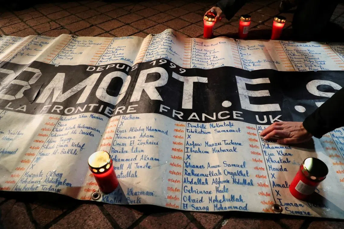 People place candles around a list of names of migrants that have died since 1999 while trying to cross the English Channel, during a tribute to the 27 migrants who died when their dinghy deflated as they attempted to cross the English Channel, at the Richelieu Park in Calais, France, November 25, 2021. REUTERS/Pascal Rossignol