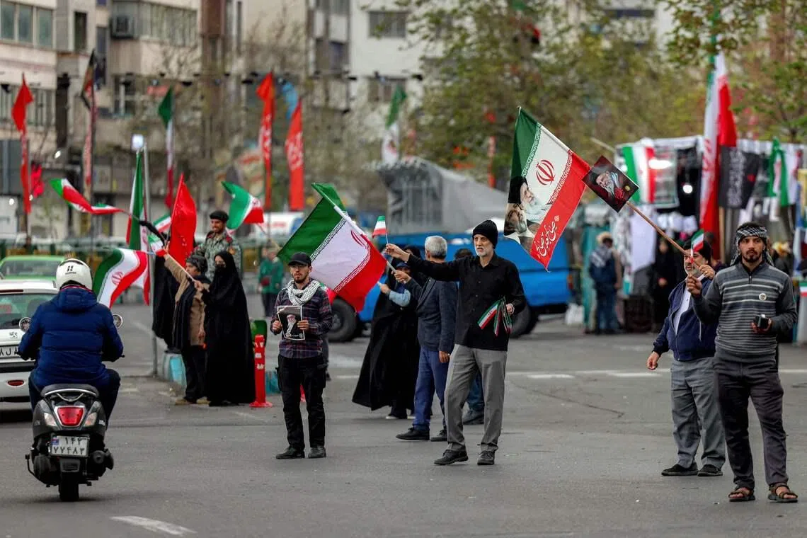 People gather with Iranian flags along Enghelab Square in central Tehran on March 25.