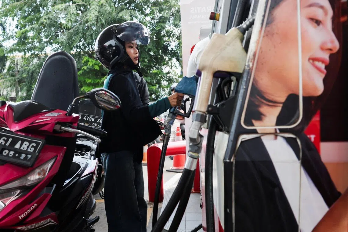 A customer holds a fuel nozzle before filling up a motorcycle at a petrol station of the state-owned company Pertamina in Jakarta, Indonesia, on March 10, 2026.