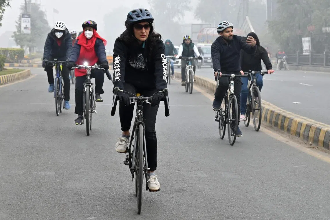 Cyclists take part in a pollution and smog awareness campaign as they ride along a street towards the Wagah border, in Lahore, Pakistan on Dec 25, 2022.