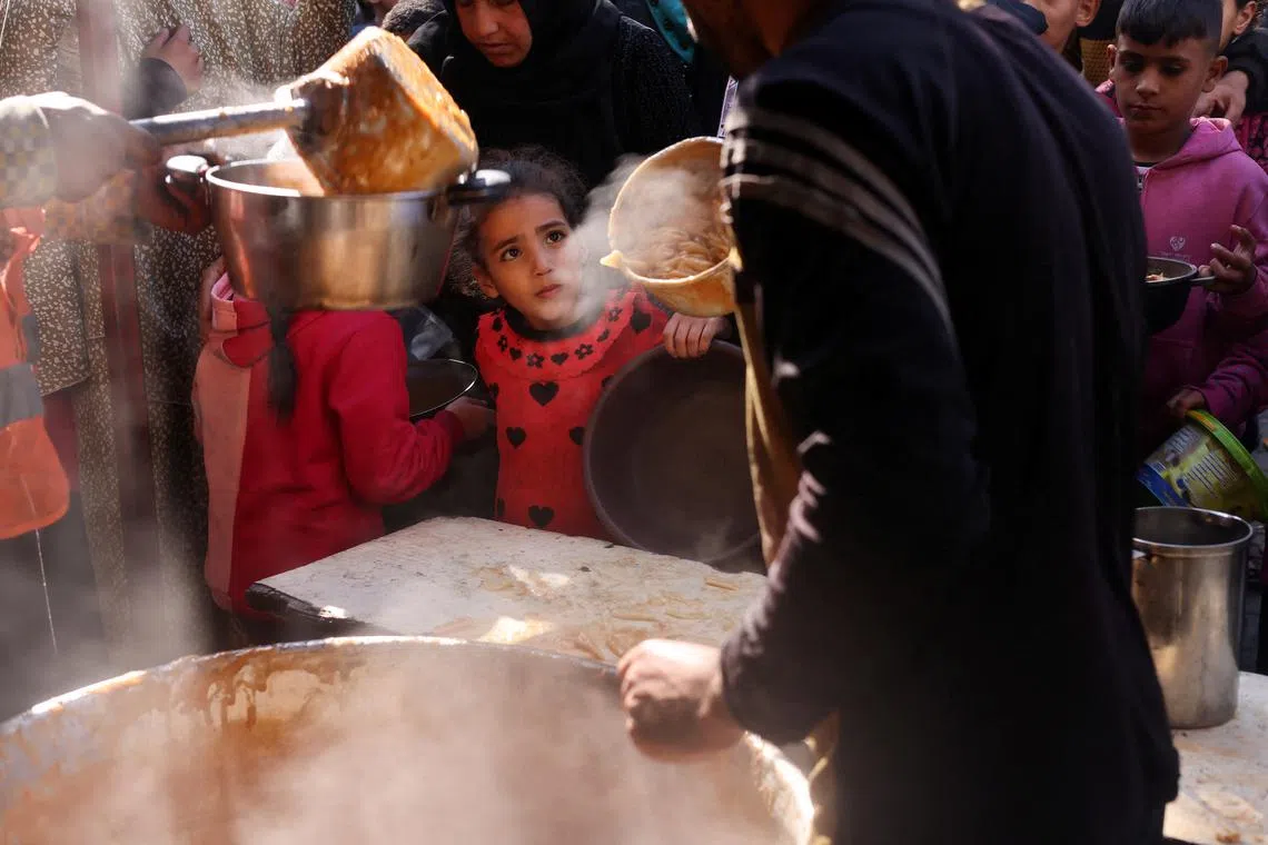 Palestinians wait to receive food cooked by a charity kitchen amid shortages of food supplies, amid the ongoing conflict between Israel and the Palestinian Islamist group Hamas, in Rafah in the southern Gaza Strip, January 16, 2024. REUTERS/Saleh Salem/File Photo