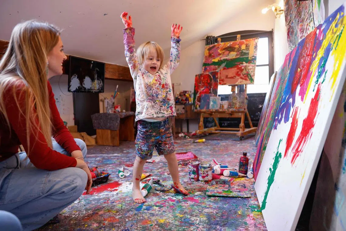 Three-year-old Laurent Schwarz reacts next to his mother Lisa while creating an artwork in his studio.