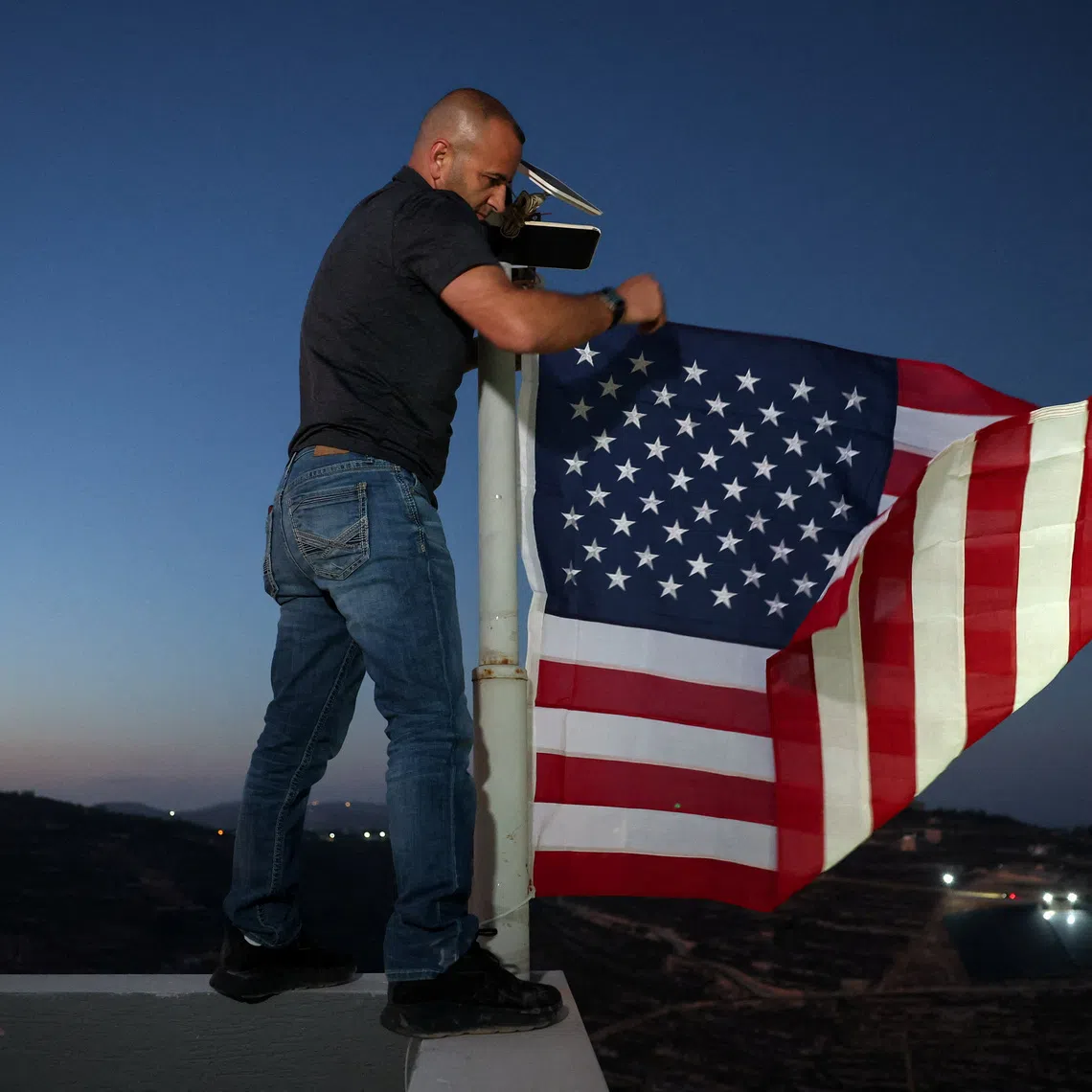 Palestinian-American Loui Ridi, whose home in the Israeli-occupied West Bank has been encircled by militant settlers for more than a week, hangs a U.S. flag after gaining access to his besieged home, in Qusra, Israeli-occupied West Bank, August 17, 2026. REUTERS/Ammar Awad