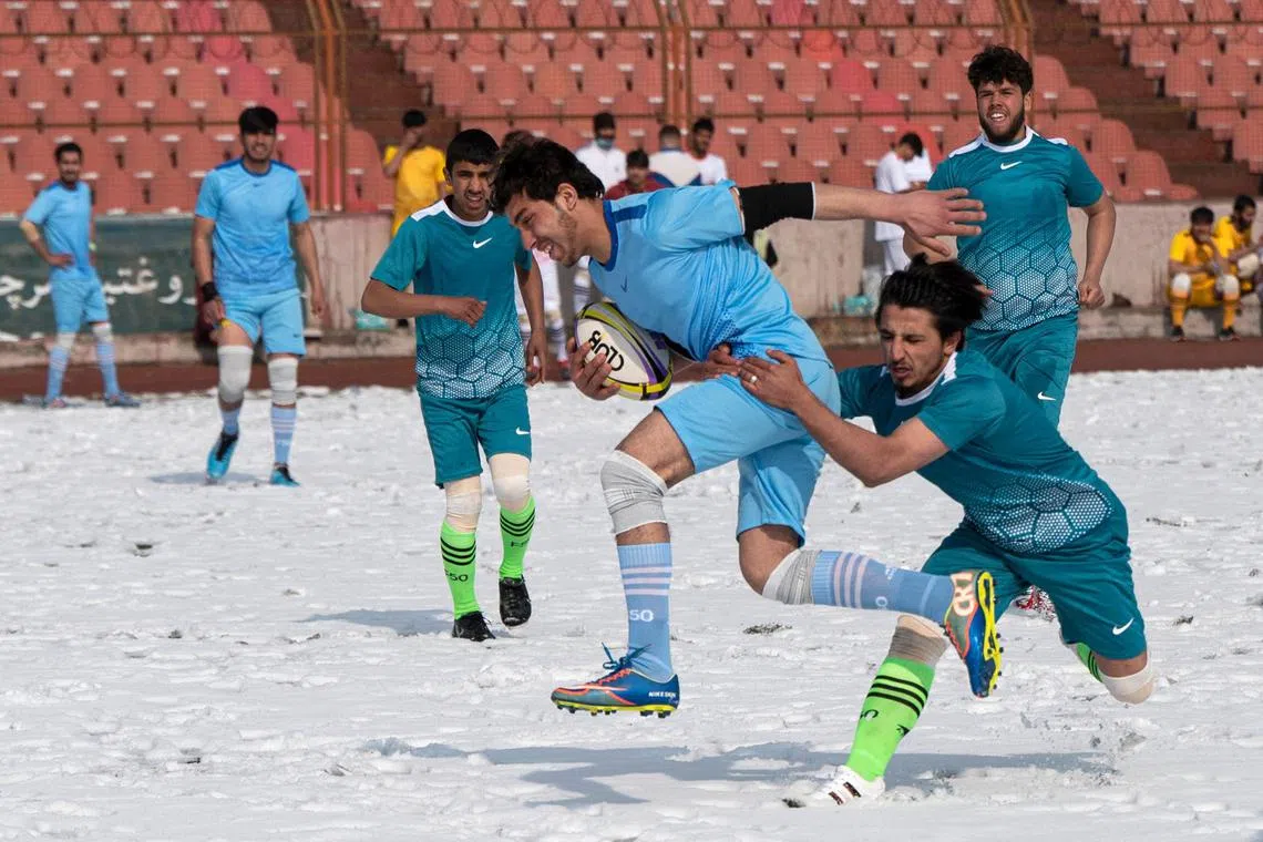 Players from Habibia High School and Ariana (in blue) compete in the Winter Rugby tournament after snowfall at Ghazi Stadium in Kabul on Jan 30, 2023. The Rugby Federation of Kabul with support from the National Olympic Committee, launched a one-day winter rugby tournament with participation from six teams from the four zones of Kabul. 