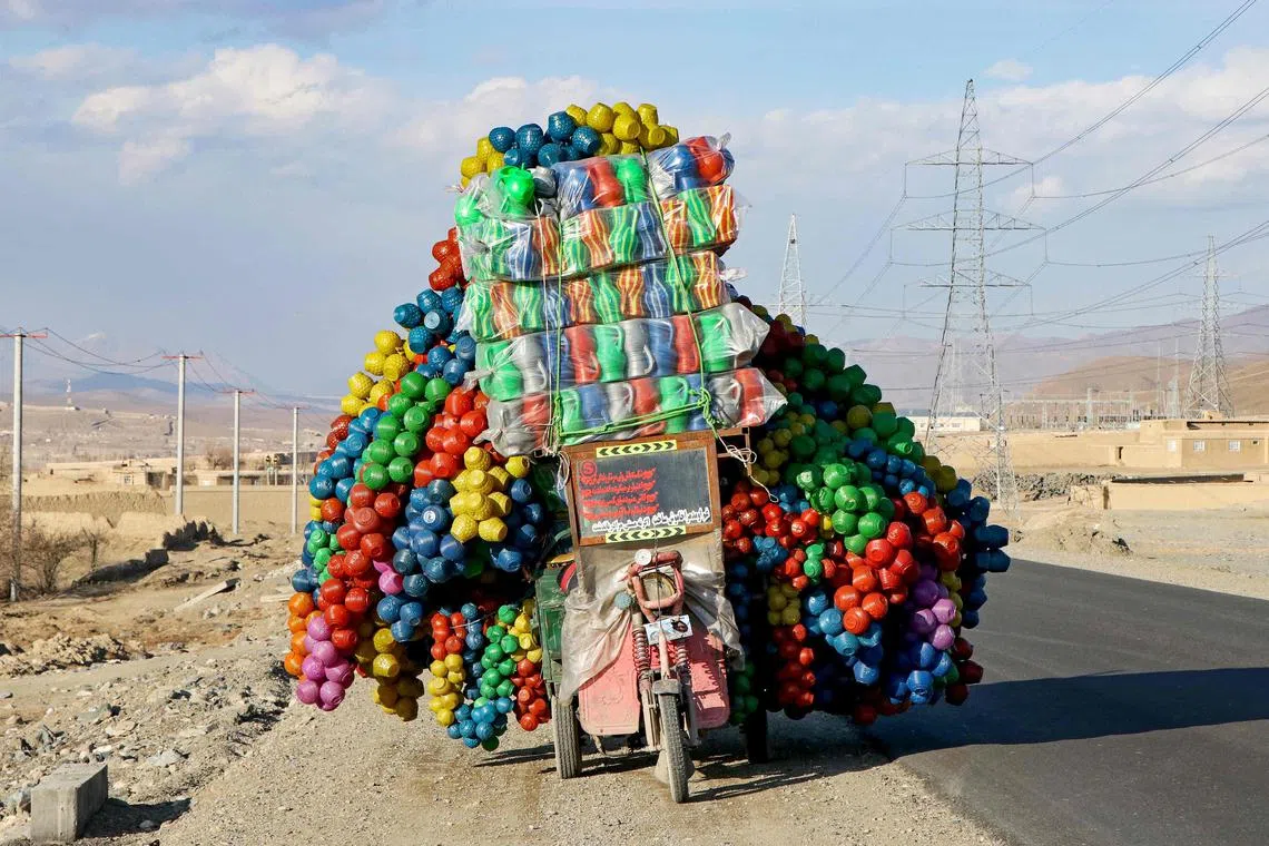 An Afghan vendor carries plastic cans on a three-wheeler rickshaw along a street on the outskirts of Maidan Wardak province on February 16, 2025. (Photo by MOHAMMAD FAISAL NAWEED / AFP)