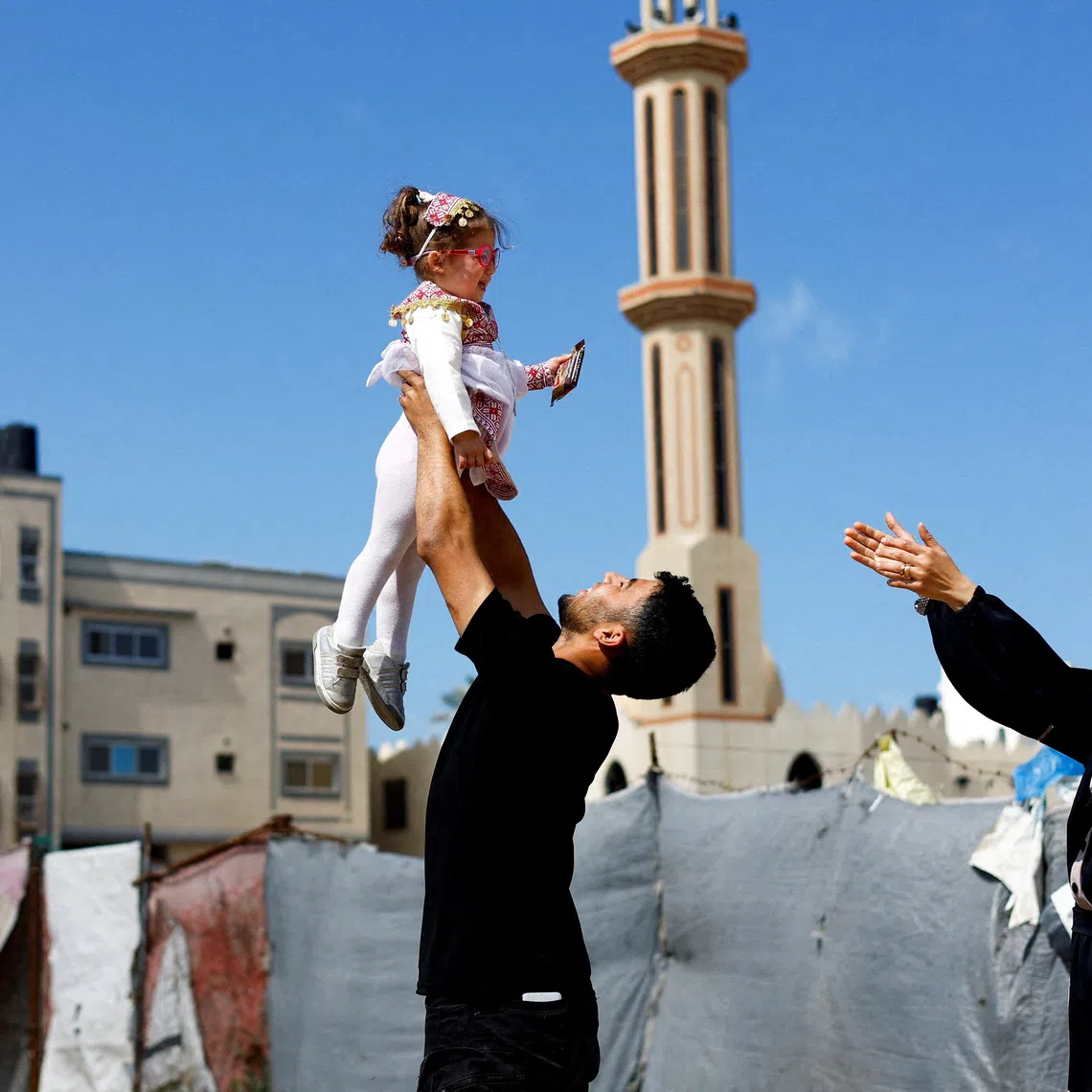 Maternal uncle of Bissan who was evacuated as a premature baby during the two-year Israeli offensive for treatment in Egypt, plays with her after she returned to Gaza as her Palestinian mother Sundus al-Kurd, 29, reaches her arms out, in Deir al-Balah in the central Gaza Strip, March 31, 2026. Bissan was one of a group of 29 preterm infants evacuated from a neonatal hospital ward as Israel's invading forces drew close. \"Bissan has begun to understand who mama really is, who her mother really is,\" Sundus said. \"I am the only person present in her life. I am the one who feeds her, changes her clothes, combs her hair, and plays with her.\" REUTERS/Mahmoud Issa