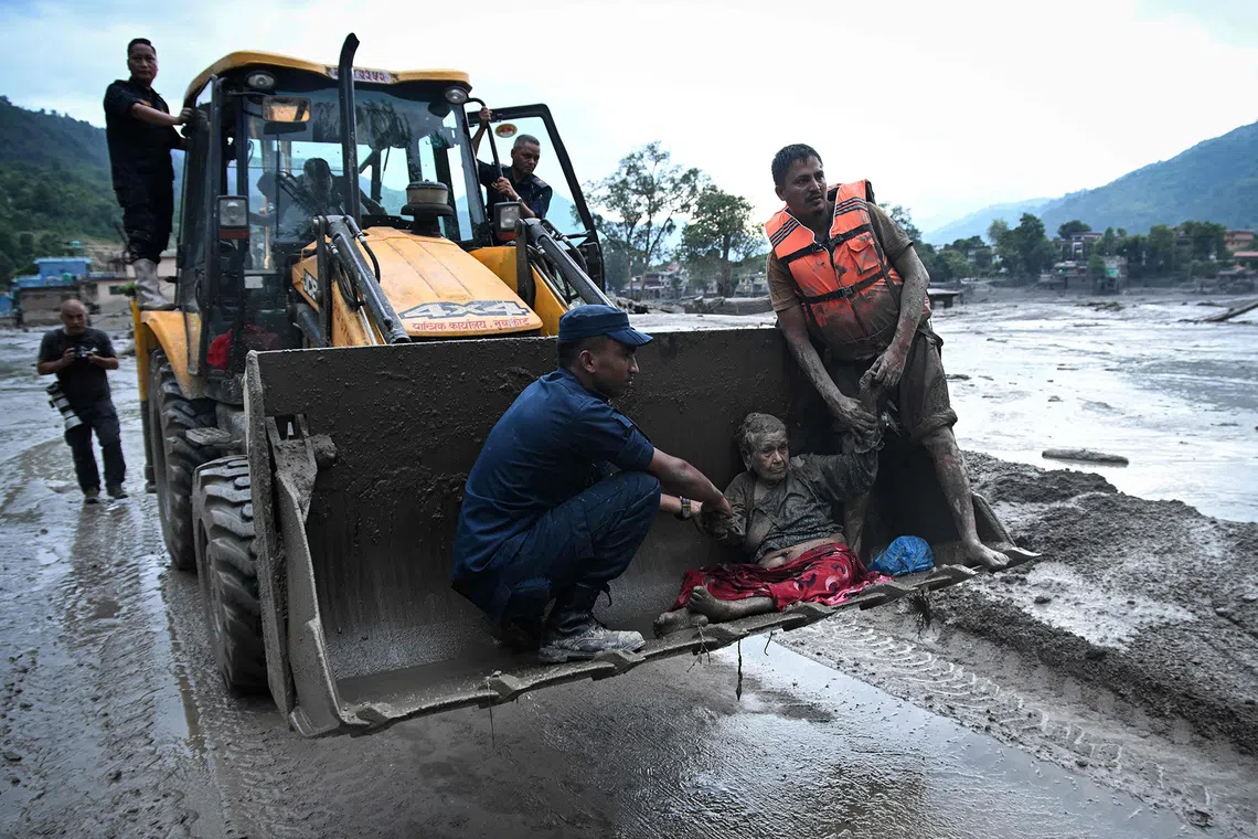 Rescuers use an excavator to transport a flood survivor, following flash floods and a landslide disaster in Devghat, in the Nepal's Nuwakot district on August 26, 2026. A massive flood and landslide disaster on the Nepal-Tibet border killed at least 103 people on August 26, 2026 and left several hundred missing, many of them foreign tourists. Aid workers said entire settlements had been "wiped out". Some 403 tourists -- 341 of them foreigners -- were unaccounted for several hours after the disaster struck, according to the tourism ministry. (Photo by PRAKASH MATHEMA / AFP)