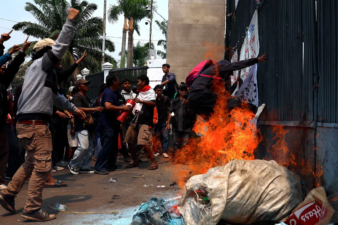 Protesters kick the gate during a protest against corruption outside the parliament building in Jakarta.