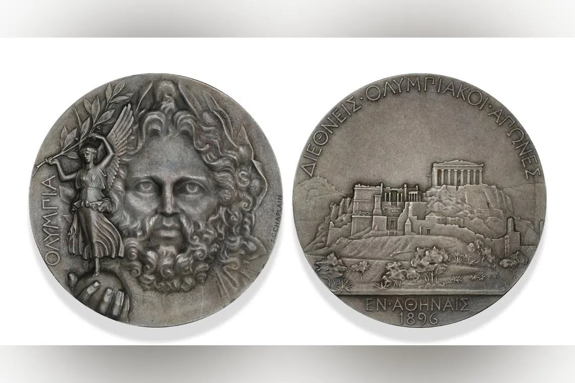 Engraved by French artist Jules-Clement Chaplain, the medal features Zeus holding a globe topped by Nike, the Goddess of Victory, brandishing an olive branch.