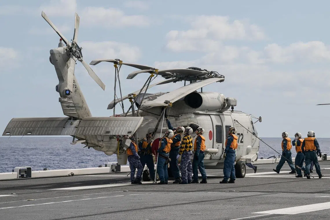 Crew members checking an SH-60K helicopter on the deck of the Japan Maritime Self-Defense Force's Hyuga-class helicopter destroyer "JS Ise", on Jan 31, 2024.