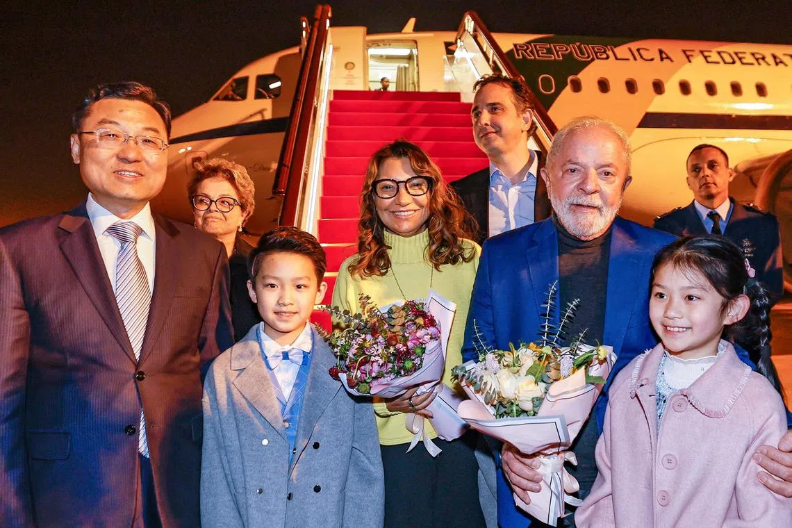 Brazil's President Luiz Inacio Lula da Silva (in blue jacket) holds flowers next to First Lady Rosangela "Janja" da Silva and China's Vice Minister of Foreign Affairs Xie Feng, as he arrives in Shanghai, on April 13.
