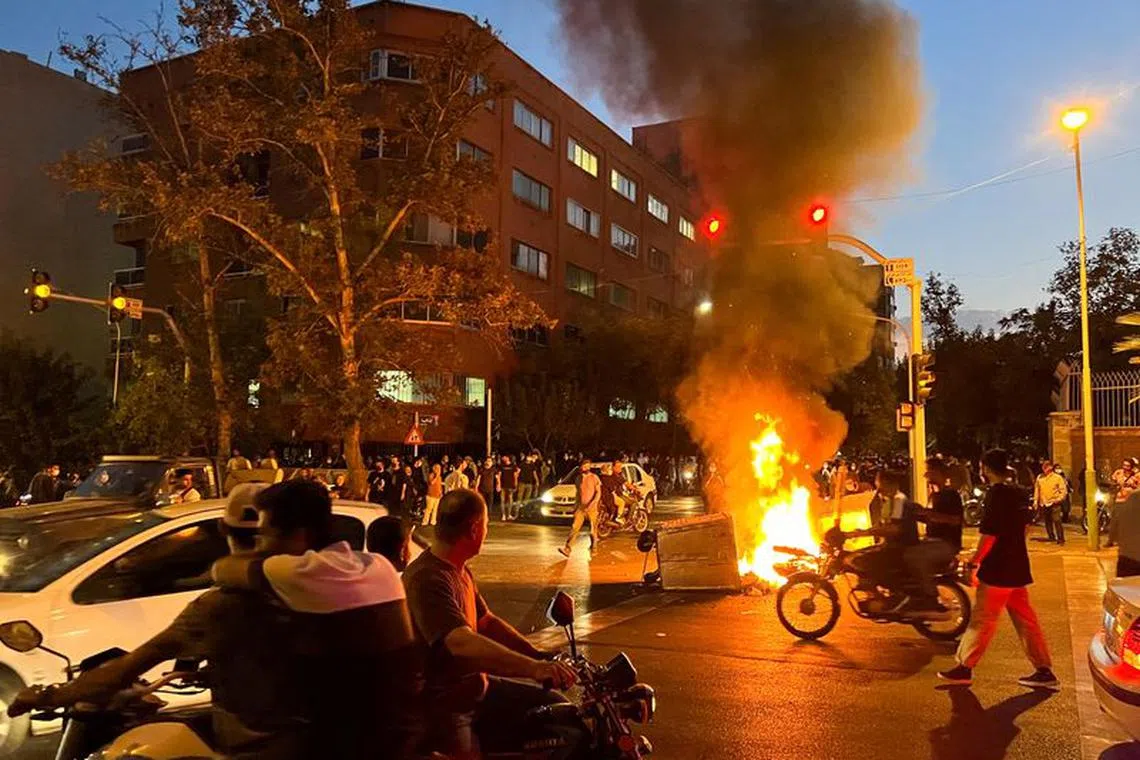 FILE PHOTO: A police motorcycle burns during a protest over the death of Mahsa Amini, a woman who died after being arrested by the Islamic republic's \"morality police\", in Tehran, Iran September 19, 2022. WANA (West Asia News Agency) via REUTERS/File Photo