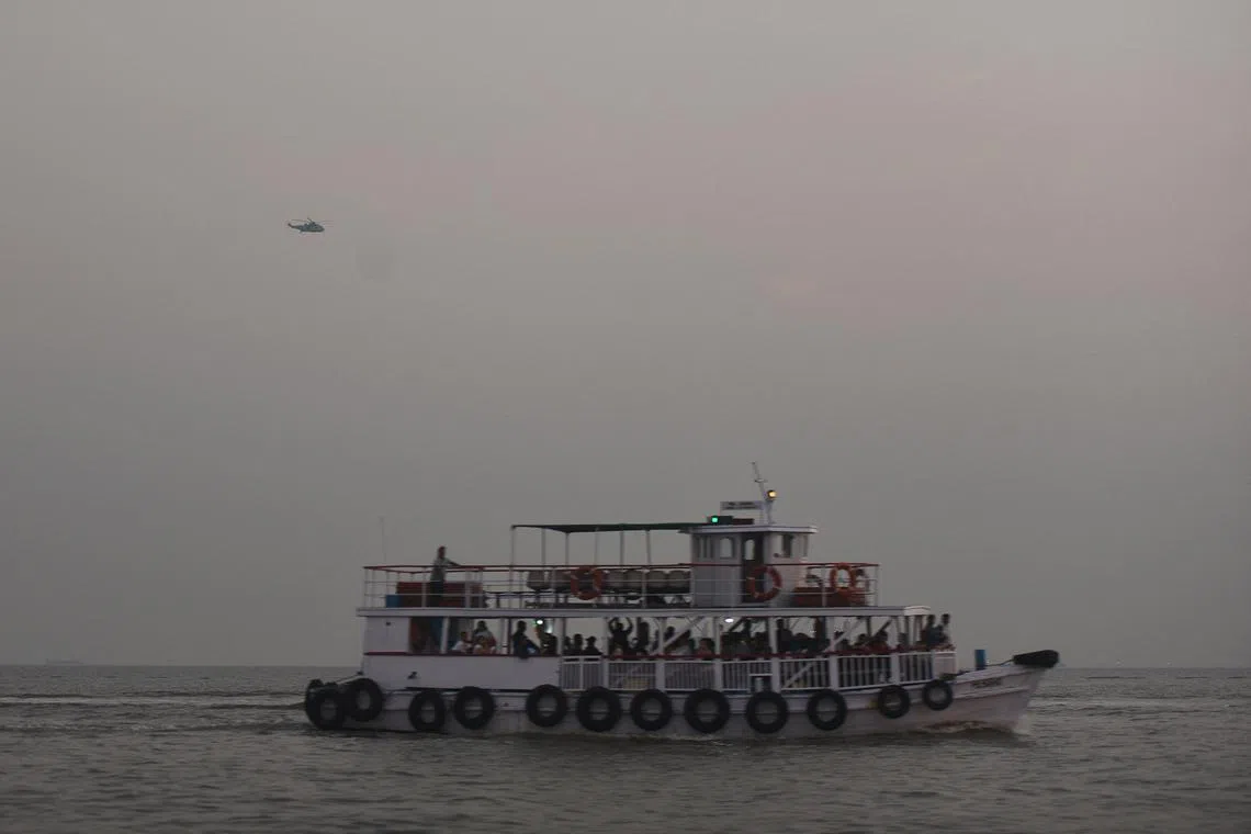 A military helicopter flies over a ferry during a rescue operation after a passenger boat capsized off the coast of India's financial capital Mumbai, India, December 18, 2024. REUTERS/Stringer