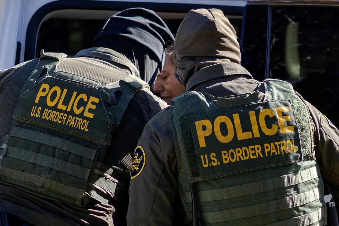 Federal agents detain a woman in a residential neighborhood during an immigration raid in Chicago, Illinois. REUTERS/Jim Vondruska