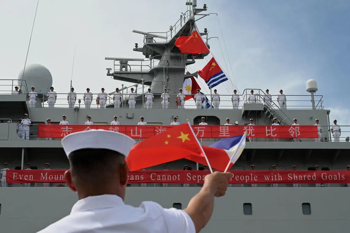A member of the Philippine Navy waving flags to welcome the arrival of the Chinese naval training ship “Qi Jiguang” in Manila on June 14, 2023. 