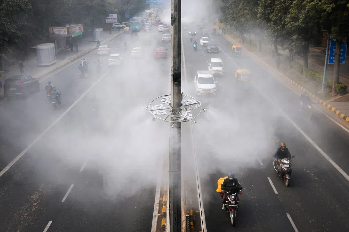 Vehicles driving past anti-smog misting system installed on a road to control air pollution in New Delhi, India, on Dec 18, 2025. 