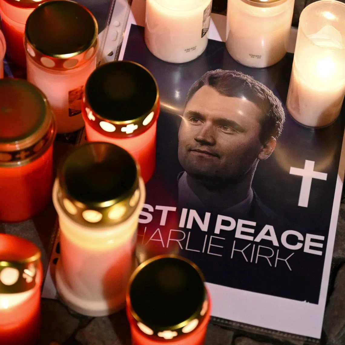 Candles are placed next to a picture of Charlie Kirk during a vigil under the line \"In Memory of Charlie Kirk, for freedom, patriotism and justice\" in front of the Embassy of the United States after U.S. right-wing activist, commentator, Charlie Kirk, an ally of U.S. President Donald Trump, was shot dead during an event at Utah Valley University, Orem, U.S., in Berlin, Germany September 11, 2025. REUTERS/Annegret Hilse