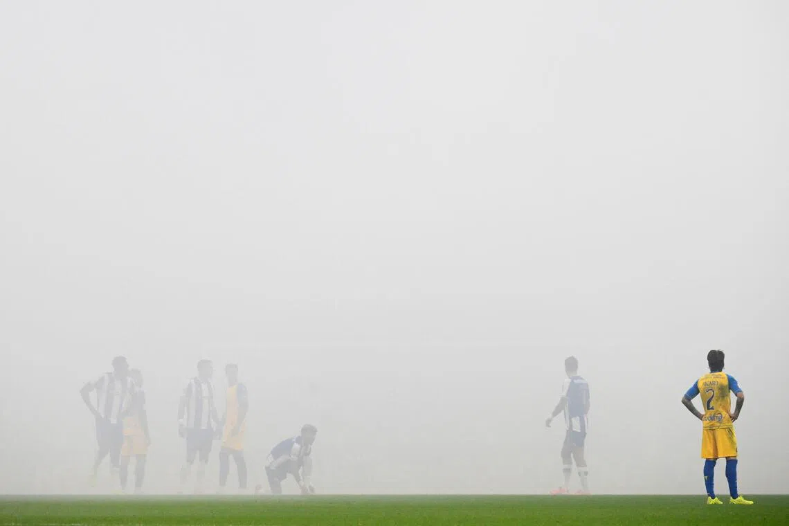 Estoril's Spanish defender #02 Ricard Sanchez and the rest of players stand on the pitch as the game is temporarily suspended due to the smoke from fans' flares during the Portuguese League football match between FC Porto and GD Estoril Praia at Dragao stadium in Porto on November 30, 2025. (Photo by Miguel RIOPA / AFP)