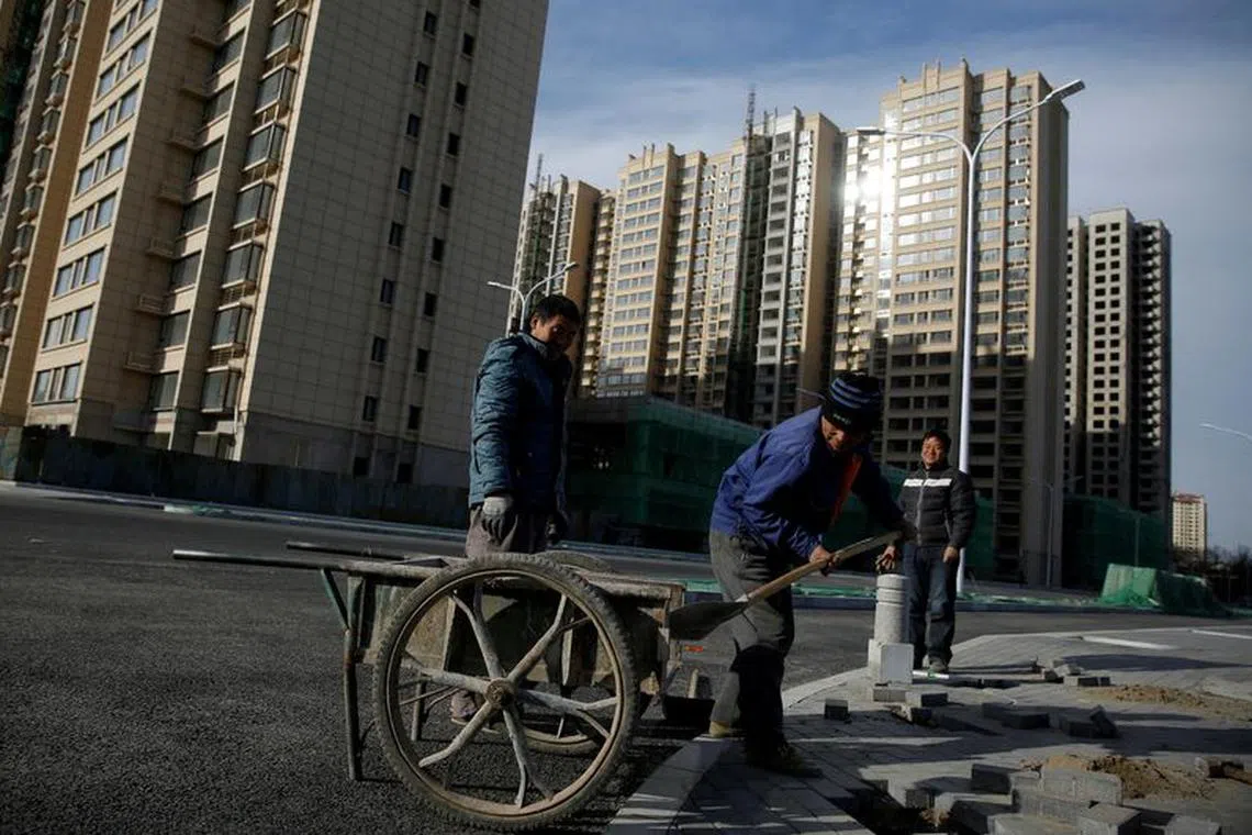 FILE PHOTO: Men work near residential apartment blocks under construction on the outskirts of Beijing, China November 29, 2017. REUTERS/Thomas Peter/File Photo