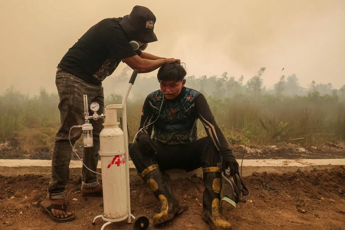 A volunteer from the Central Kalimantan Forest and Land Fire Smoke Response Coalition providing mobile oxygen relief to a firefighter in Palangkaraya, Central Kalimantan, on Oct 22.